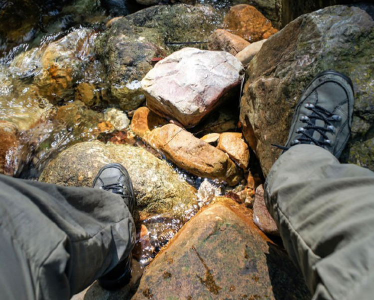 pies en el río con botas de montaña