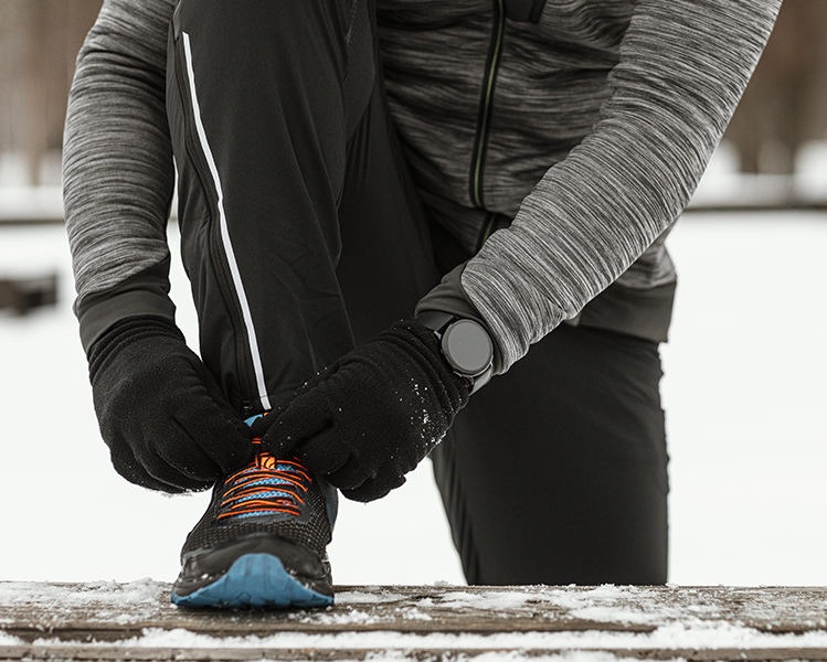 hombre atando zapatilla con nieve