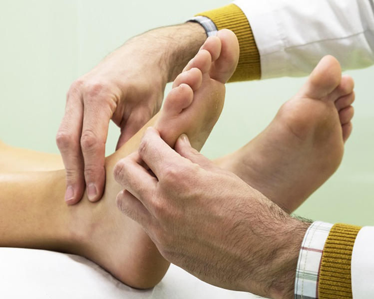 Doctor tocando con las manos las plantas de los pies