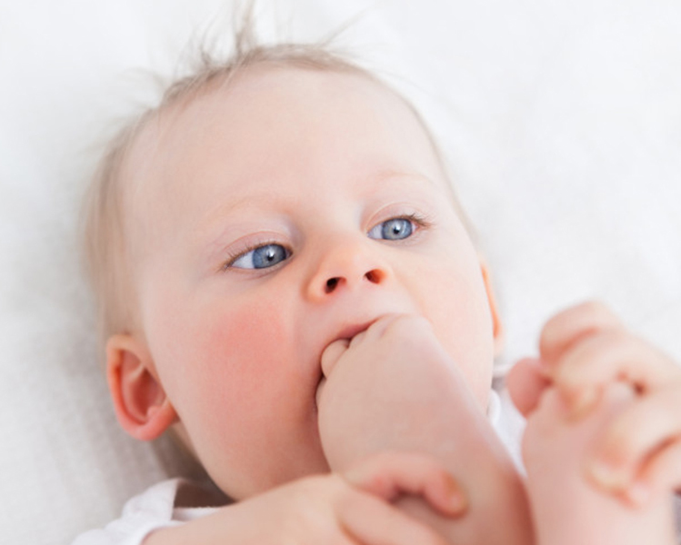 Niño de ojos azules chupando su pie