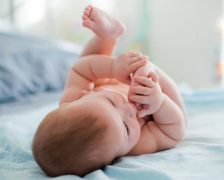 Niño tumbado en la cama chupando sus pies