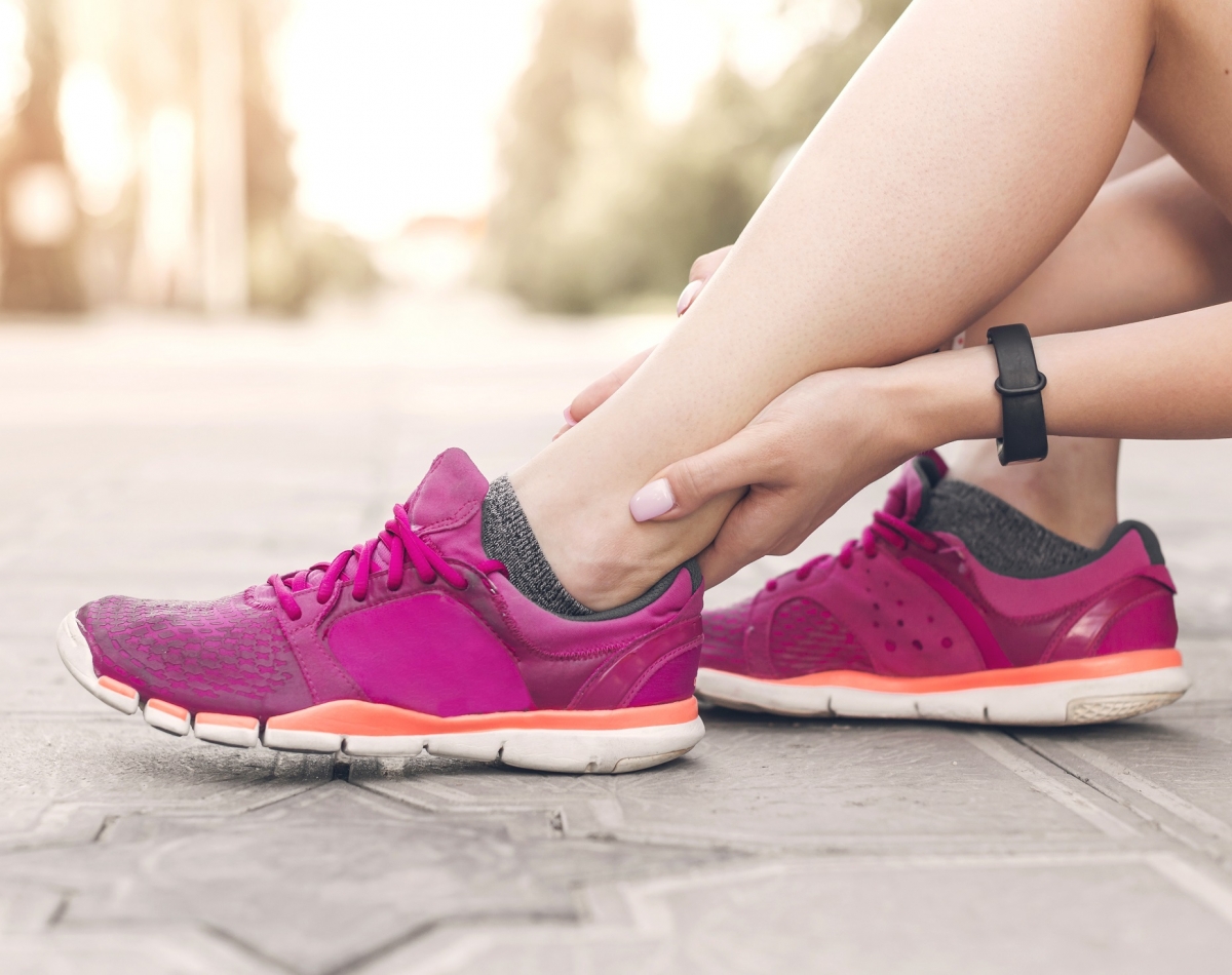 Mujer con zapatillas de running tocando la zona del tobillo